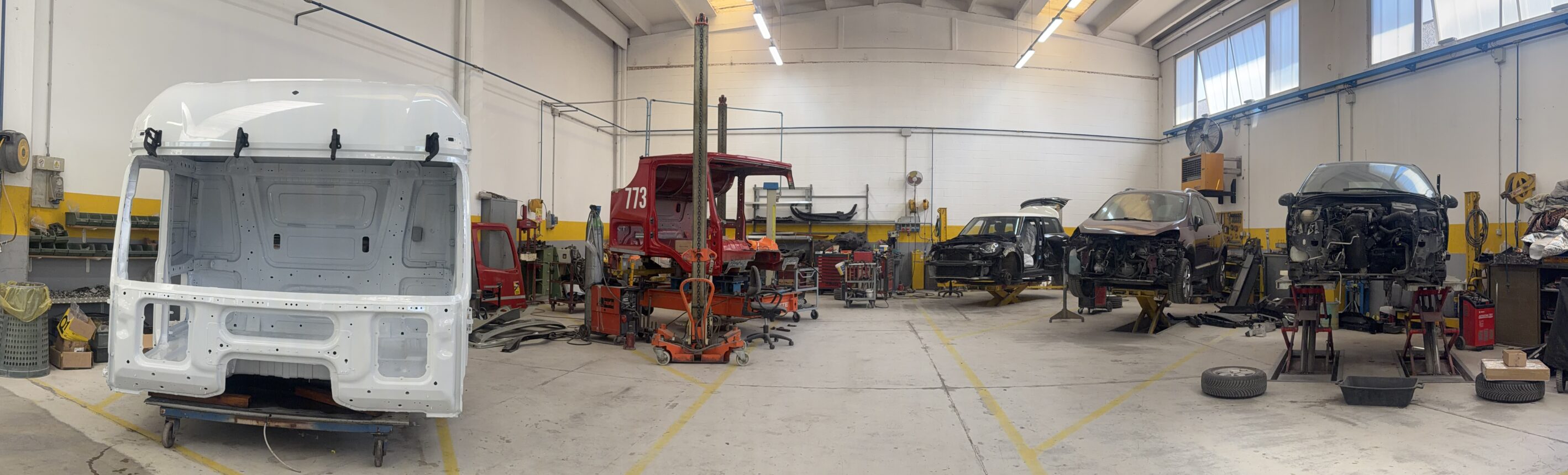 Panoramica dell'officina C.D.M. Carrozzeria con cabine di camion e auto in riparazione